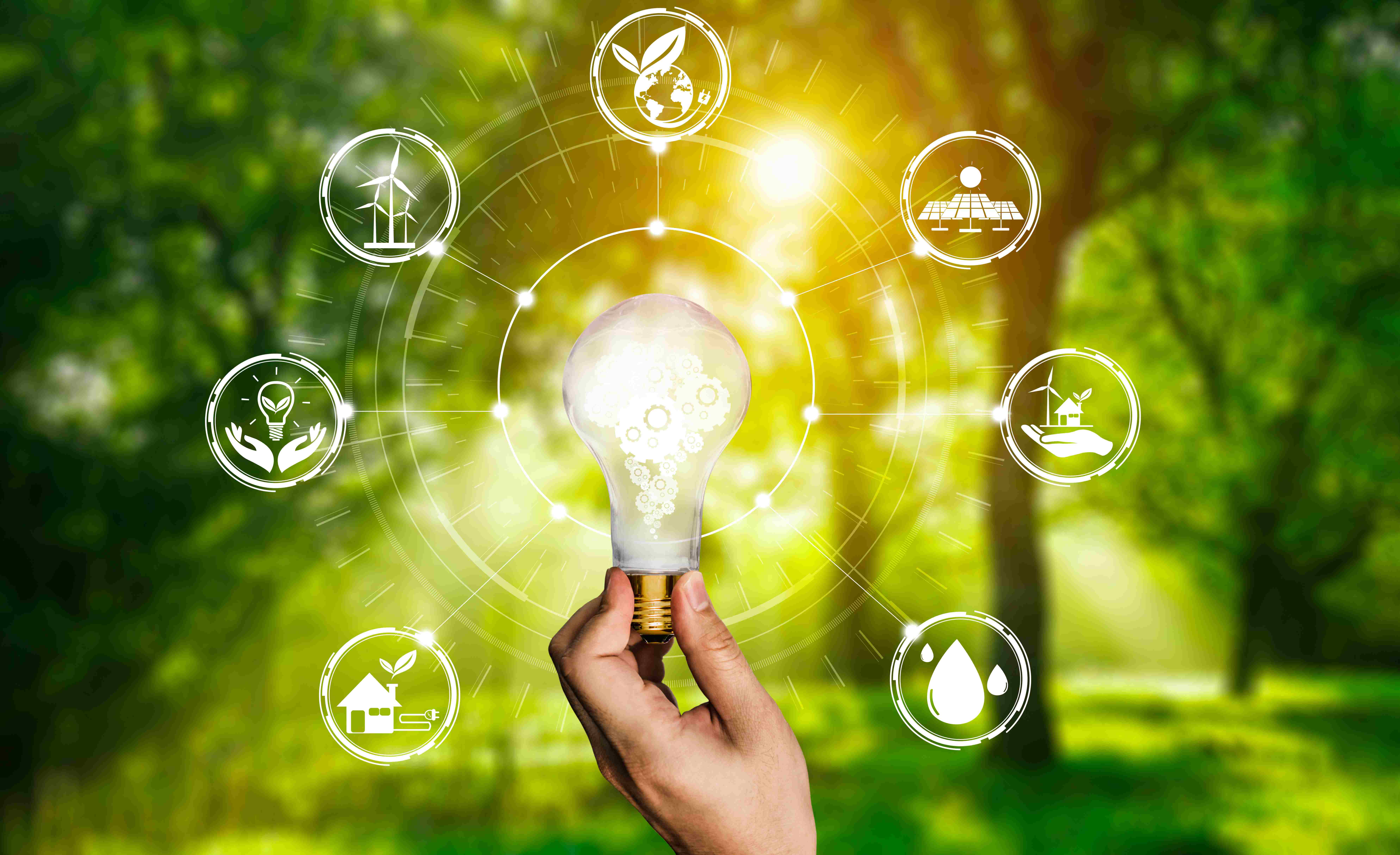 Mano sosteniendo bombilla iluminada rodeada de iconos de energías renovables - paneles solares, turbinas eólicas, sostenibilidad ambiental